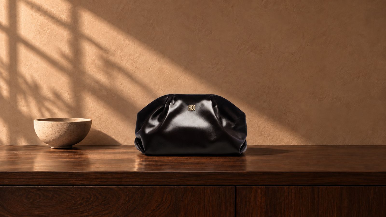 n&eacute;MOTTI black leather clutch with its gold monogram pin